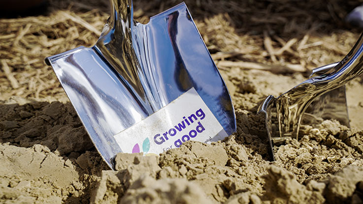 A shovel labeled ‘growing for good’ digs into fresh dirt at the new hospital site.