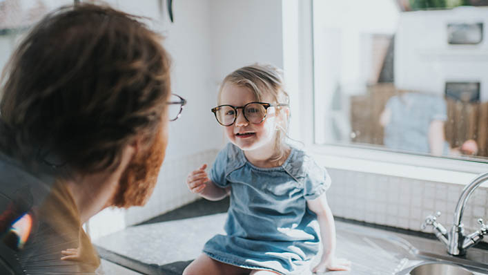 Little girl in glasses talking to doctor also in glasses.