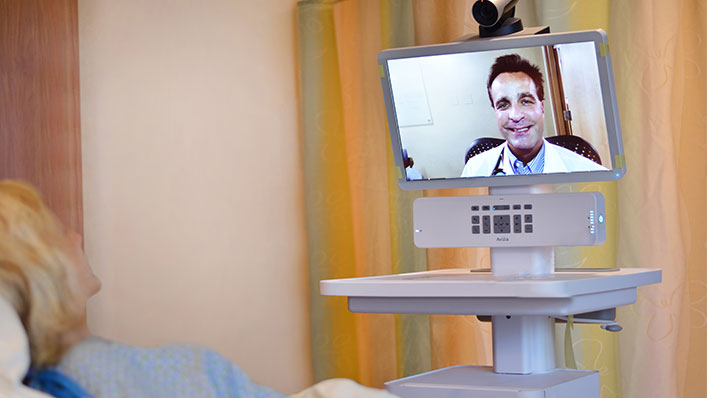 A patient in her hospital bed is having a video visit with her doctor