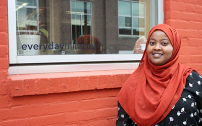 Ayan Abdullahi stands by a building window.
