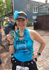 Stacy holds up a medal she earned from a running race.
