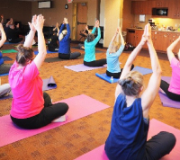 A group of women hold a seated position during a yoga class.