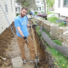 A man wearing a HealthPartners shirt does backard landscaping work as a volunteer for Habitat for Humanity ReStore.