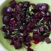 A green bowl full of chopped beets with vinaigrette.
