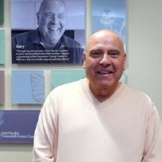 Gary Sisson poses for a photo next to his picture on the wall at the Frauenshuh Cancer Center.